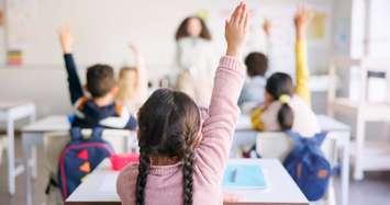 Students raising their hands in a classroom (Photo by: Jacob Wackerhausen/ iStock / Getty Images Plus)